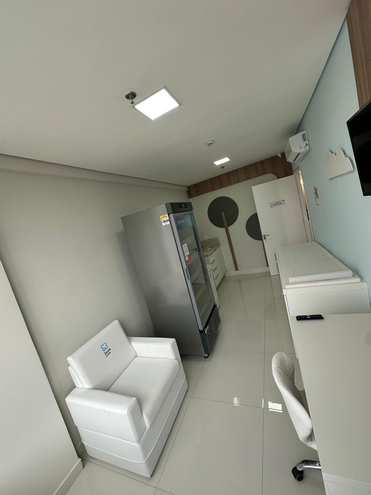 Sala de vacinação com poltrona branca e equipamentos de conservação